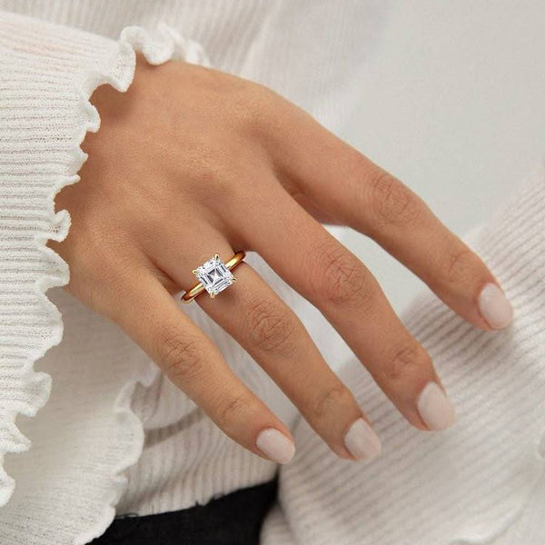2 carat June Asscher Classic Solitaire Diamond Ring worn on hand, showcasing its elegant yellow gold band and secure solitaire setting.