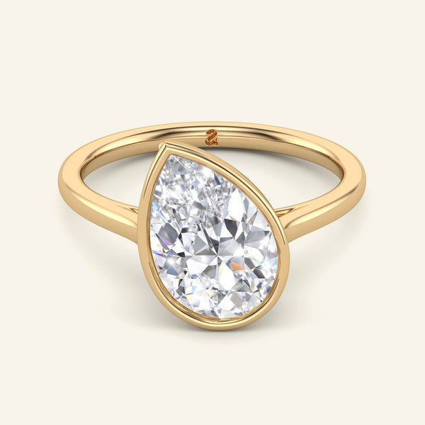 Remi Pear Bezel Solitaire Diamond Ring in yellow gold with a 2 carat tilted pear-shaped lab-grown diamond, bezel-set for a modern engagement look.