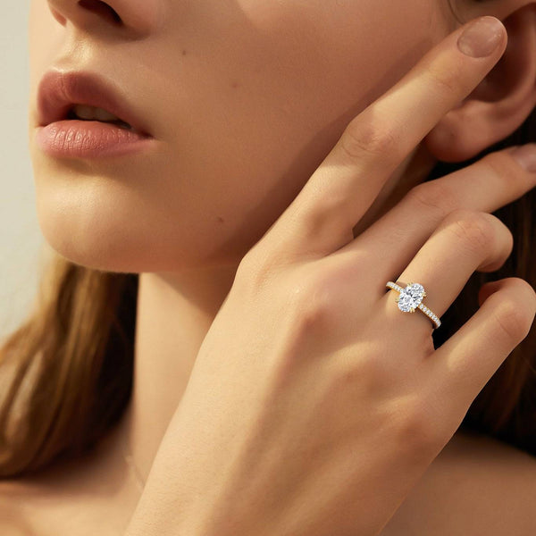 Model wearing Cora Oval Cathedral Pavé Solitaire Diamond Ring showcasing 2 carat oval cut diamond set in yellow gold with pavé detailing.