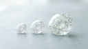 Three lab-grown diamonds of ascending size on grey, illustrating a 3 carat diamond's scale