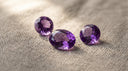 Loose violet amethyst gemstones, the February birthstone, on warm greige linen