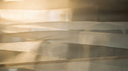 Soft layered warm champagne and greige silk in golden light, an abstract editorial backdrop for charm necklace layering
