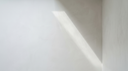 Chalk-white plaster with a soft diagonal of daylight — abstract editorial backdrop for lab-grown diamond jewellery