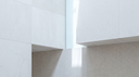 Pale stone planes with a soft shaft of daylight — abstract editorial backdrop for lab-grown diamond necklaces