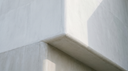 Cool stone planes meeting at a soft edge — abstract editorial backdrop for solid gold vs gold-plated vs gold-filled