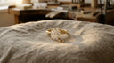 Oval-cut lab-grown diamond solitaire engagement ring in yellow gold on warm greige linen