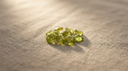 Loose lime-green peridot gemstones, the August birthstone, on warm greige linen