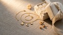 Solid gold charm necklace with sun, moon and heart charms beside a jewelry gift box and silk ribbon