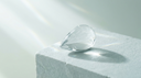 Pear-cut lab-grown diamond engagement ring concept — clear teardrop crystal on pale stone in soft daylight