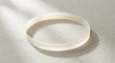 Abstract editorial image of a continuous ribbon of soft light forming an unbroken circle on cool pale linen, evoking full and half eternity rings