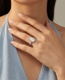 Close-up of a hand wearing a diamond ring with a neutral background